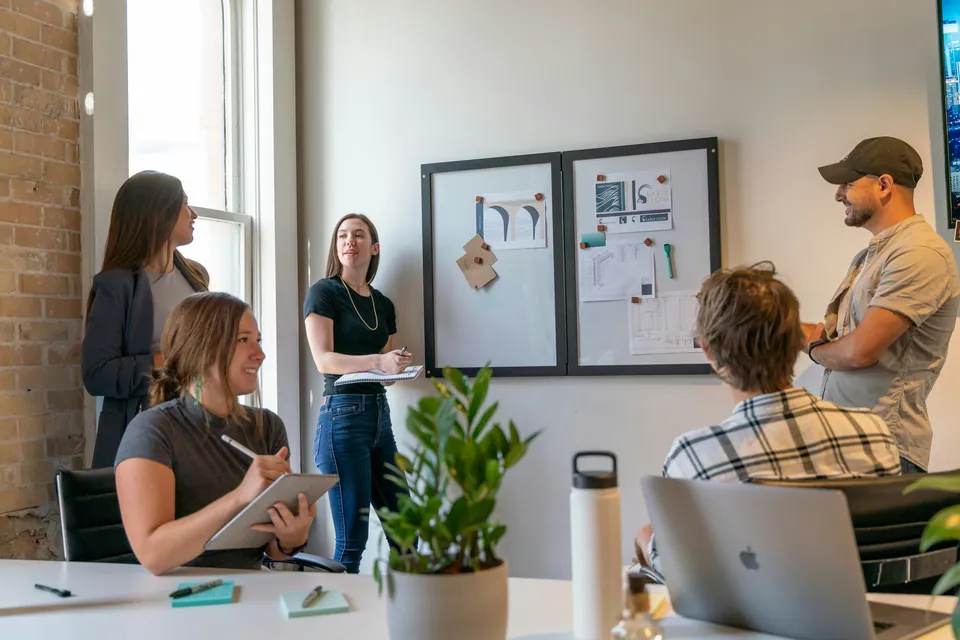 Startup team meeting around a pinboard in a bright office