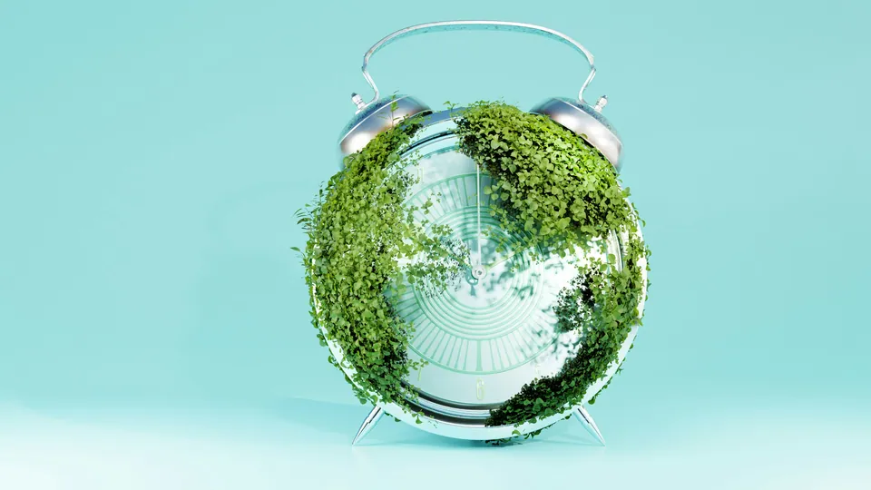Alarm clock covered in green moss on a teal background