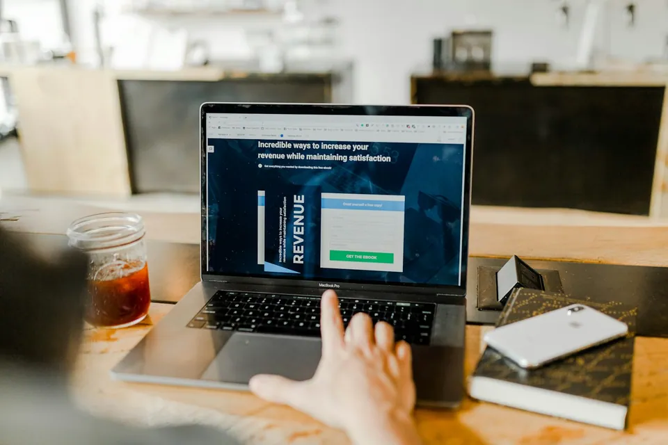 Hand typing on a laptop showing a revenue growth web page