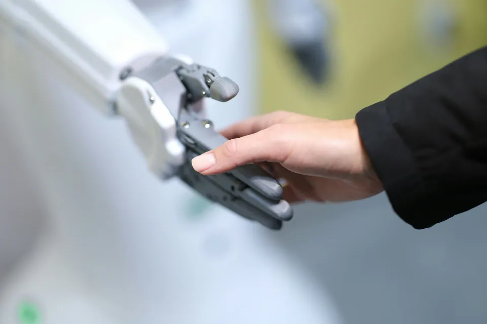 Human hand touching a robotic hand