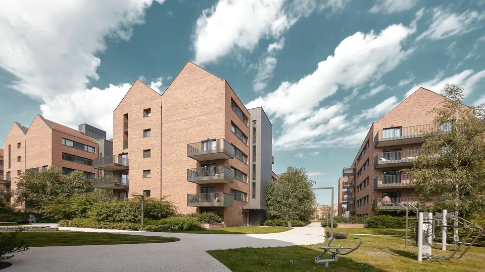 Modern red brick apartment buildings with balconies around a landscaped courtyard