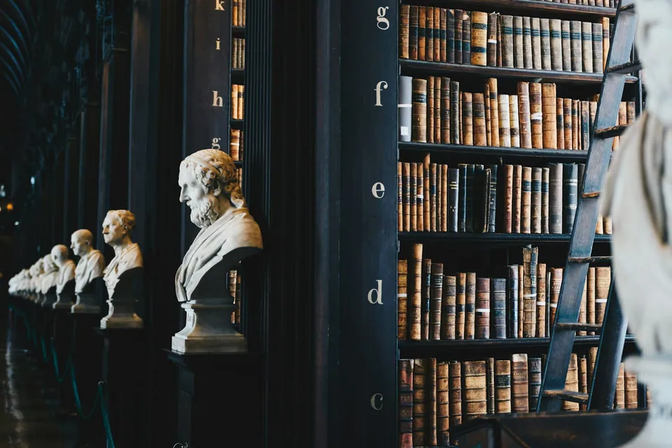 Library hall with tall bookshelves and a row of marble busts