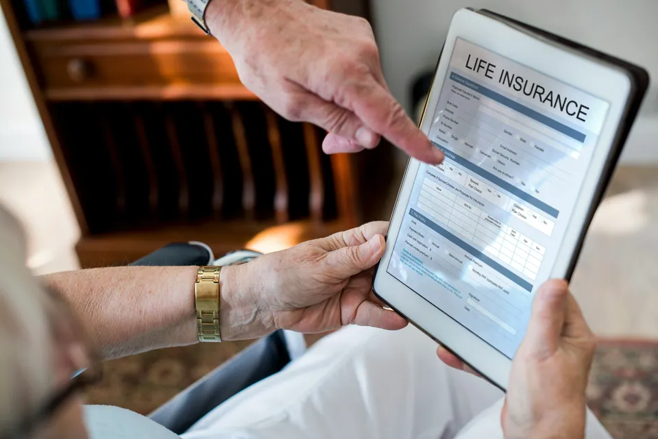 Hands pointing at a life insurance form on a tablet