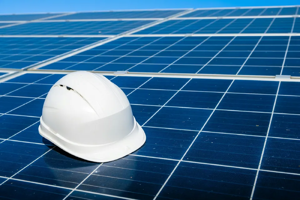 White hard hat resting on rows of solar panels