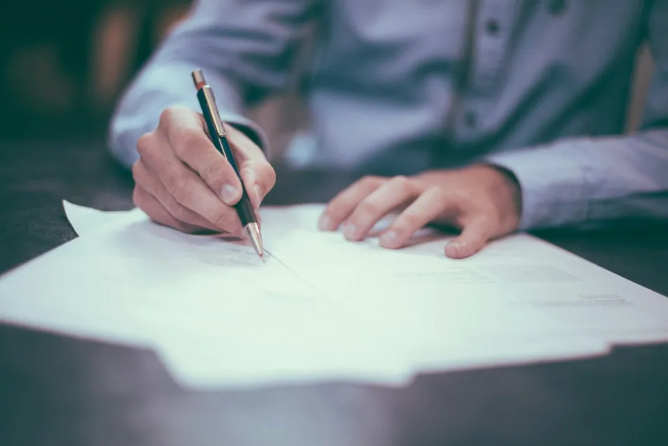 Hand signing a sheet of paper with a fountain pen