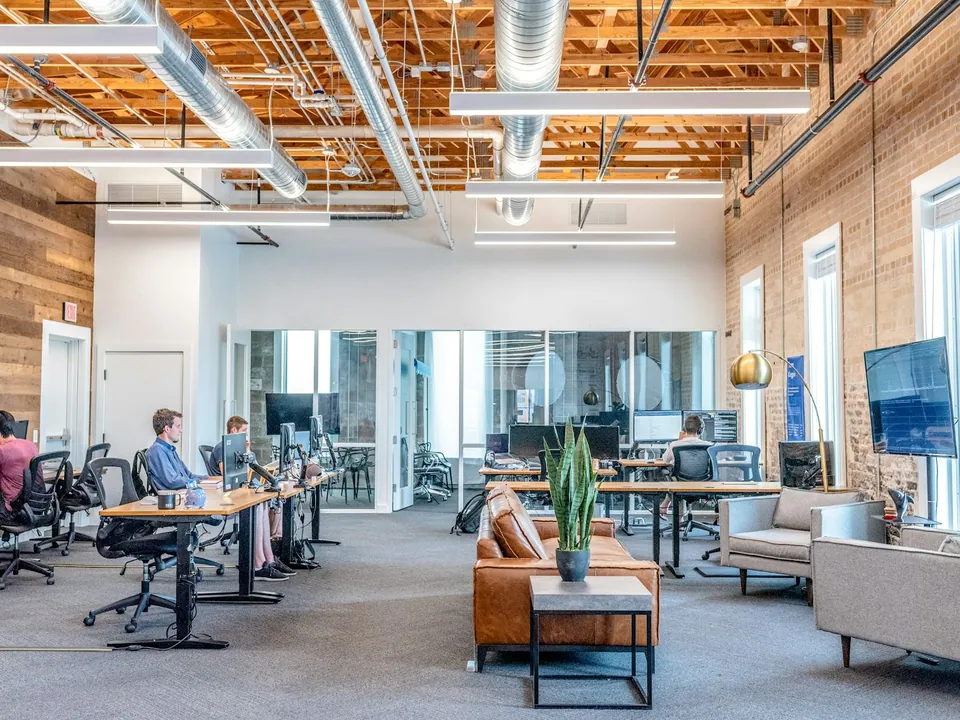 Open-plan office with standing desks and exposed wooden ceiling