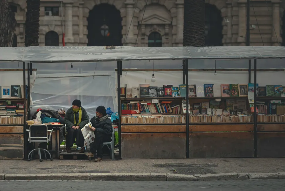 Street-side used book stalls with vendors seated in front
