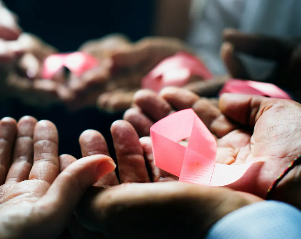 Open hands holding pink awareness ribbons