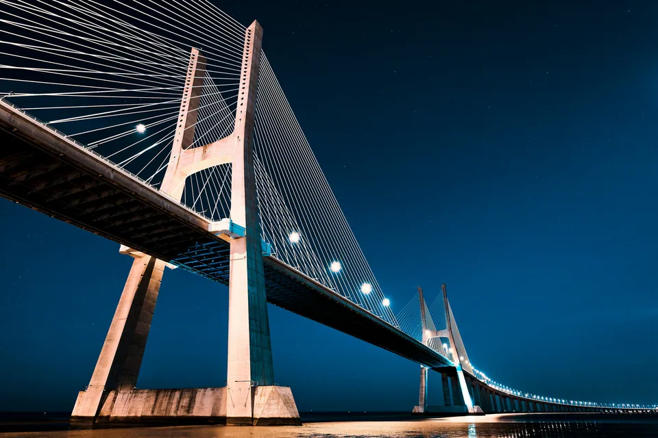Cable-stayed bridge lit up against a deep blue night sky