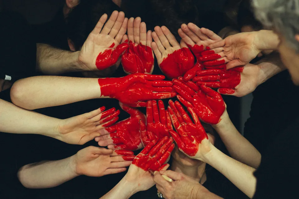 Many hands painted red joined together in a circle