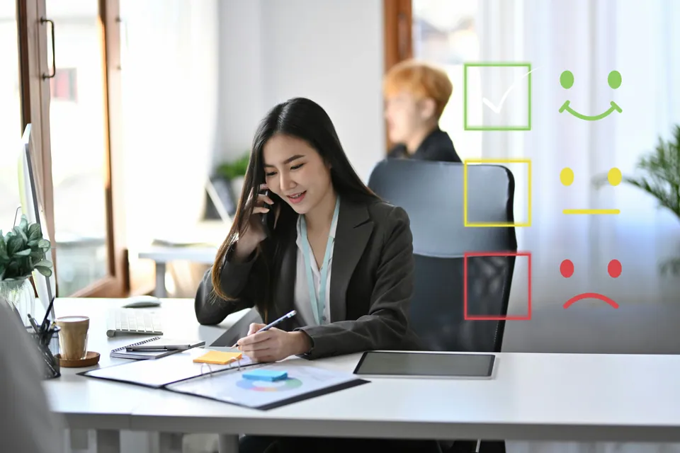 Businesswoman on the phone at her desk beside satisfaction rating icons