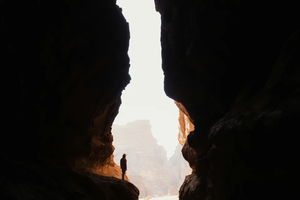 Silhouette of a person standing in a narrow canyon opening