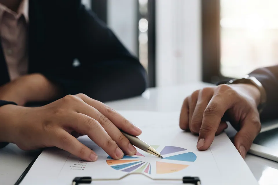 Hands with a pen reviewing a printed pie chart