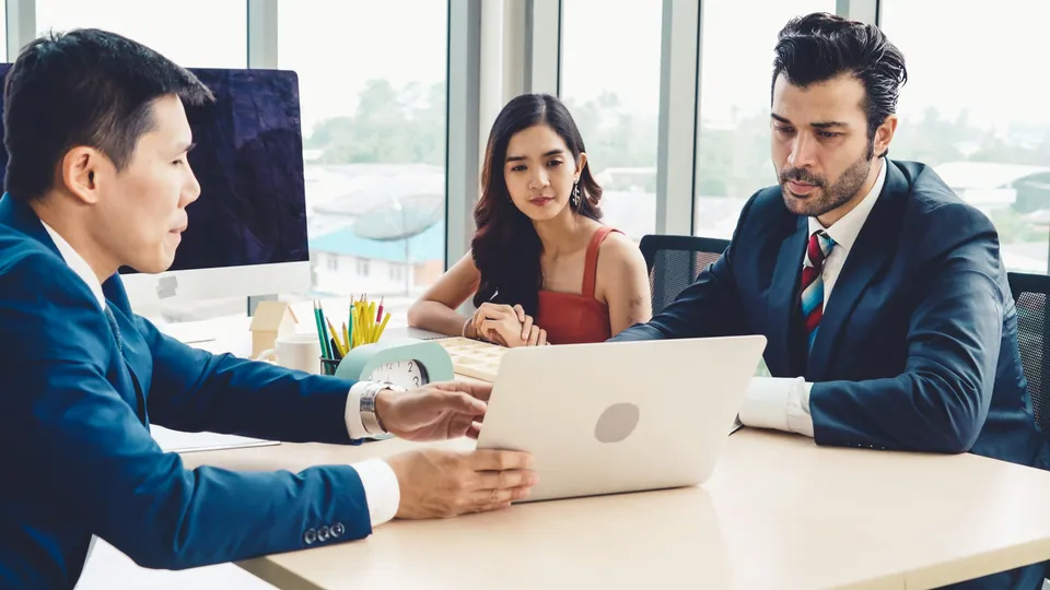 Advisor meeting a couple across a desk with a laptop