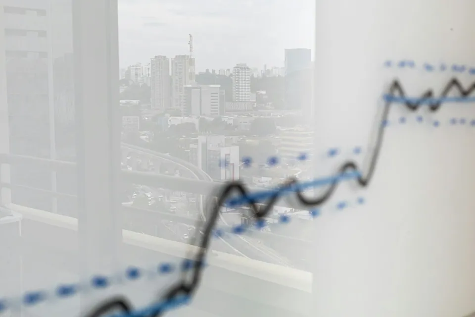 Rising line chart drawn on a window overlooking a city