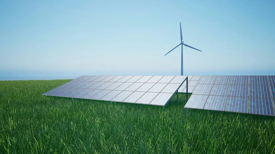 Solar panels on green grass with a wind turbine behind
