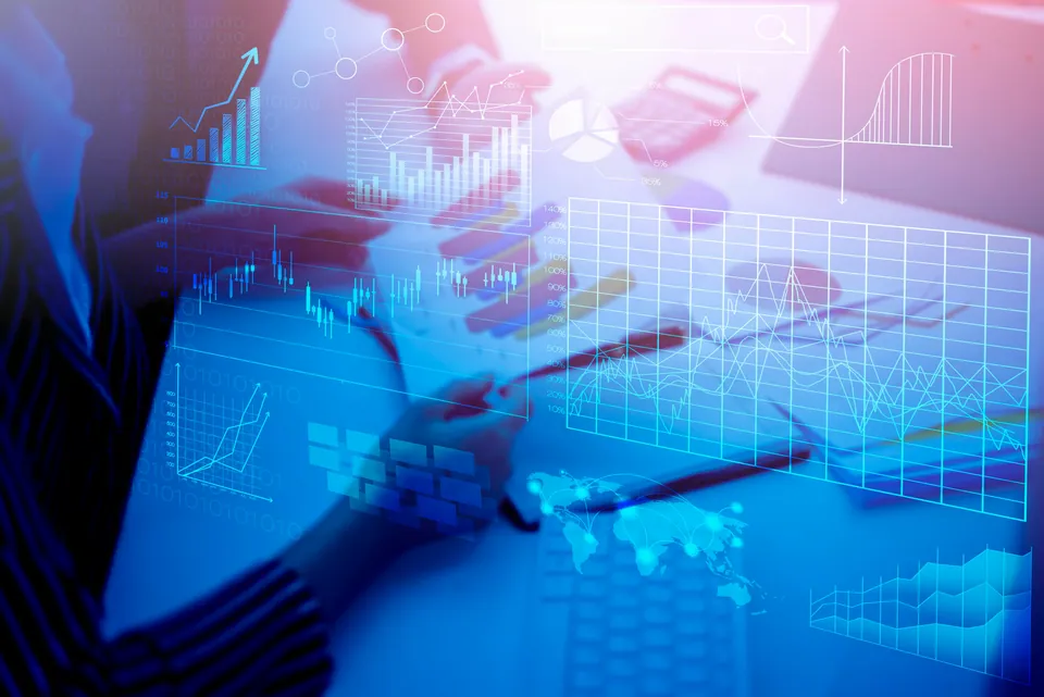 Hands over a desk overlaid with glowing blue financial charts