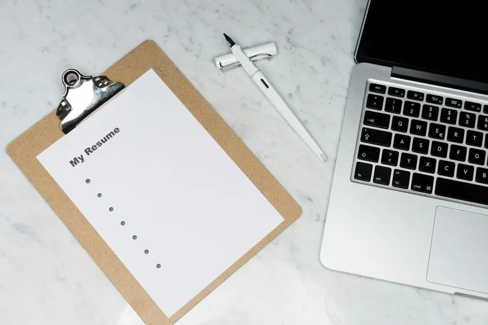Clipboard with a blank resume checklist next to a laptop