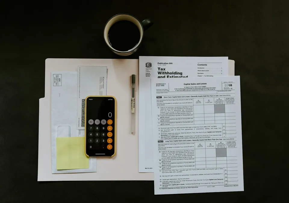 Tax withholding form with a phone calculator and coffee on a dark desk