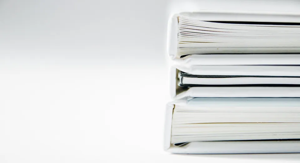 Stack of white ring binders on a white background