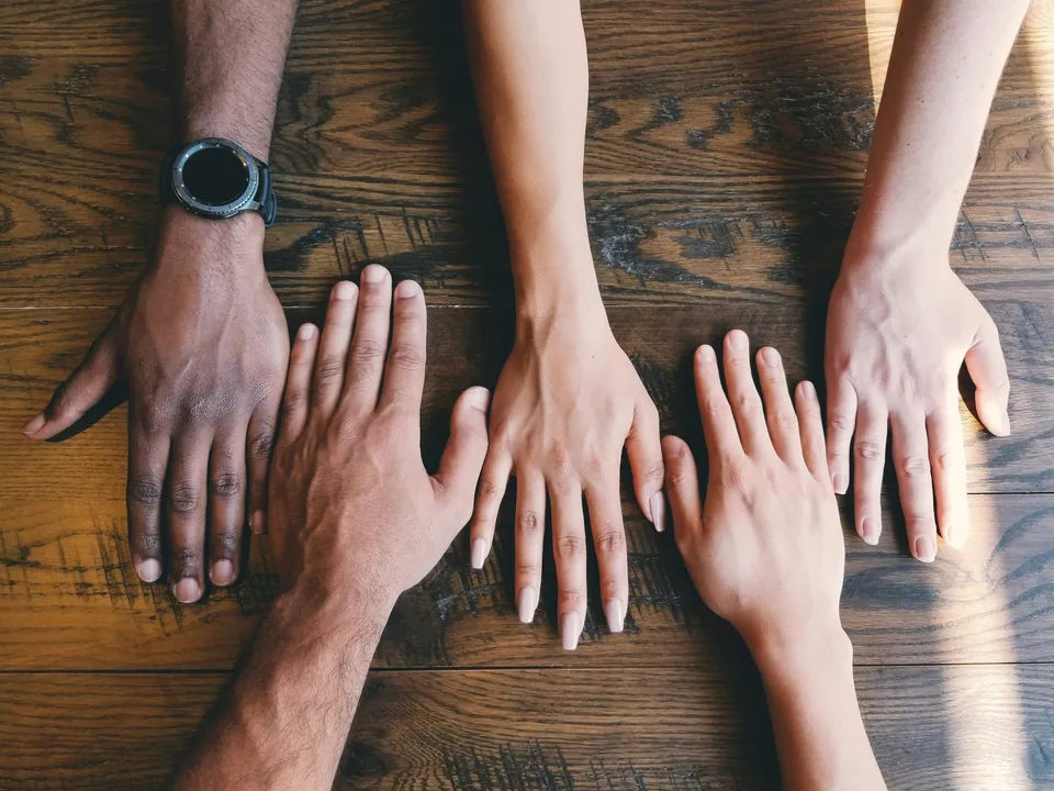 Diverse hands laid side by side on a wooden table