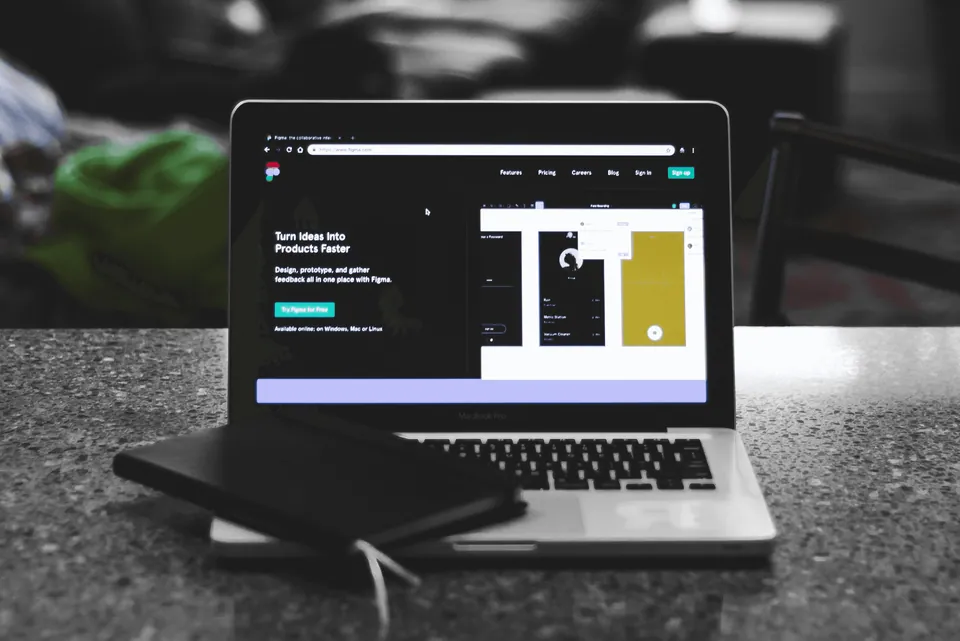 Laptop showing a design app landing page on a stone counter
