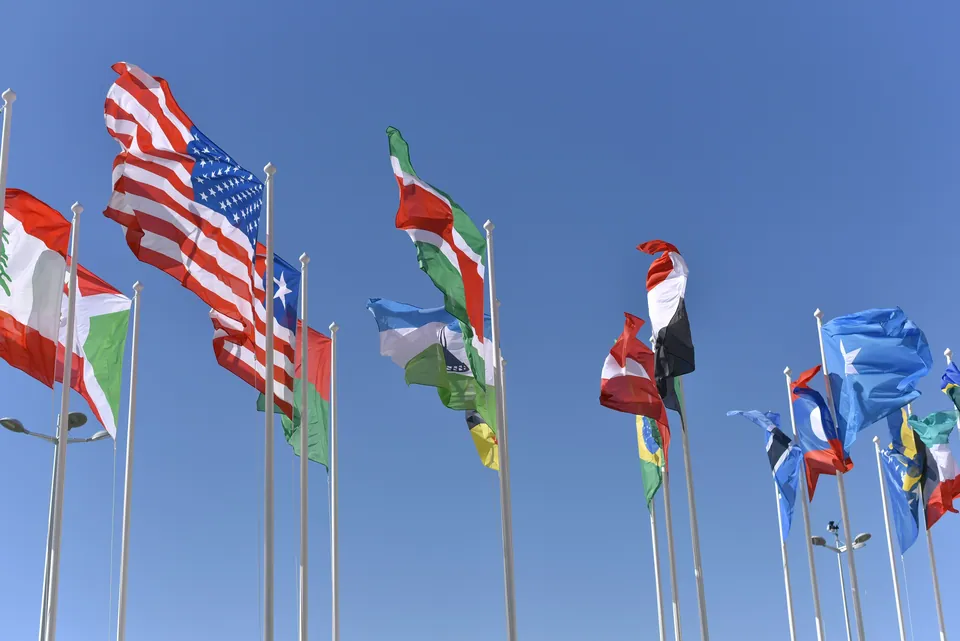 International flags flying on poles against a blue sky