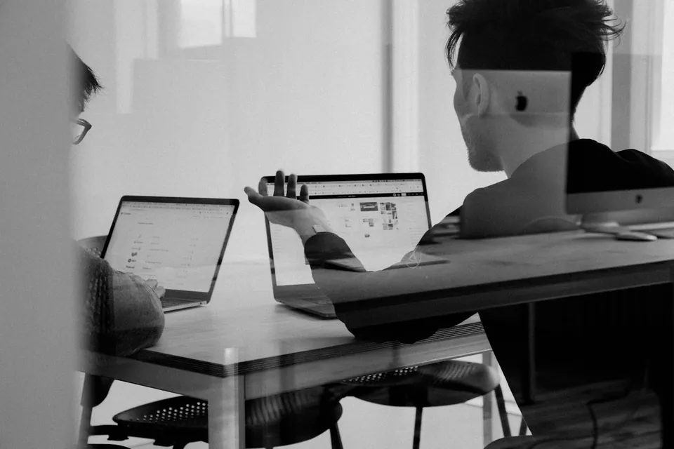 Black and white photo of people working on laptops in an office