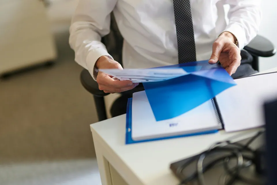 Businessman sorting blue folders and documents at a desk