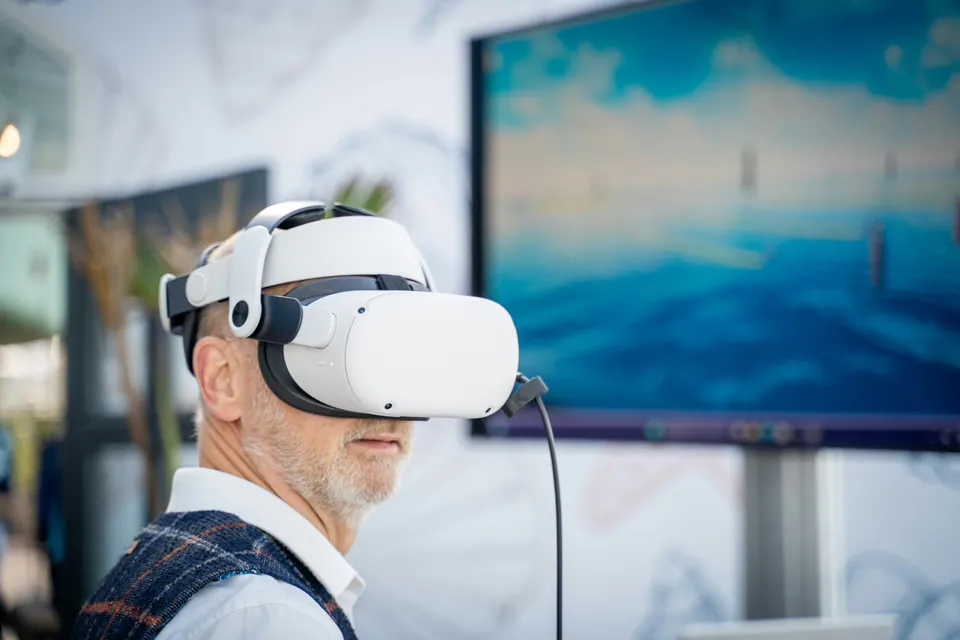 Older man wearing a white VR headset in an office