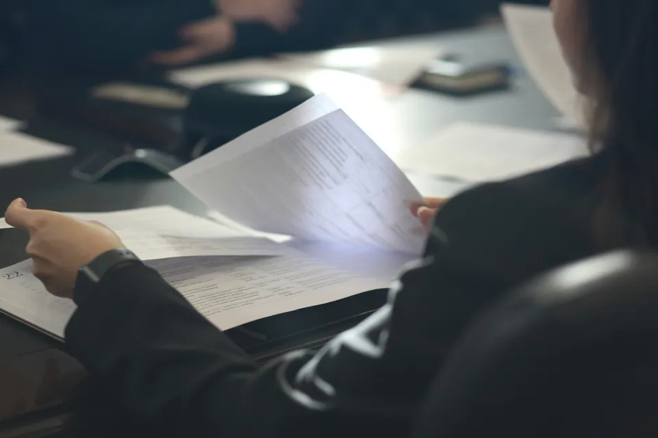 People reviewing printed documents at a dark table