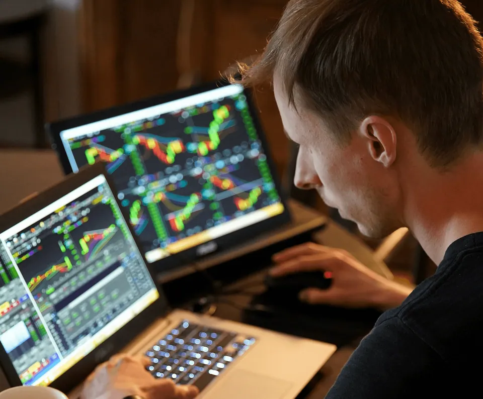 Trader studying colorful stock charts on two laptops