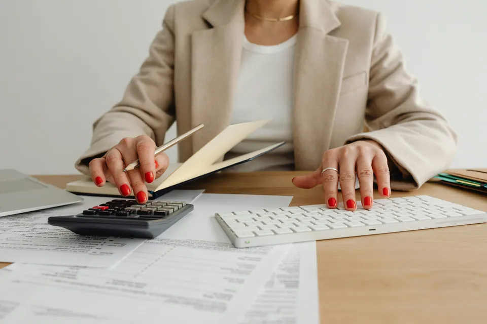Woman with red nails using a calculator over paperwork