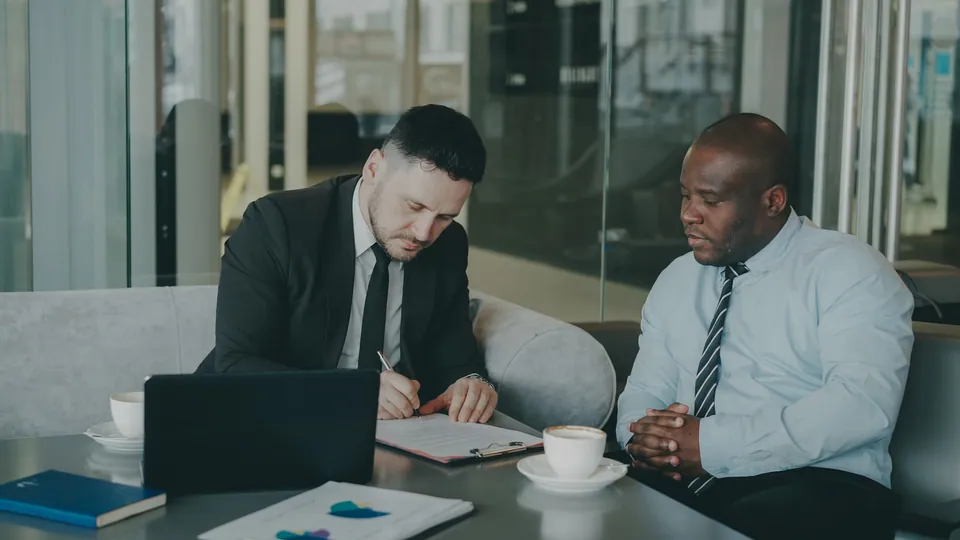 Two businessmen in a meeting at a coffee table with a laptop