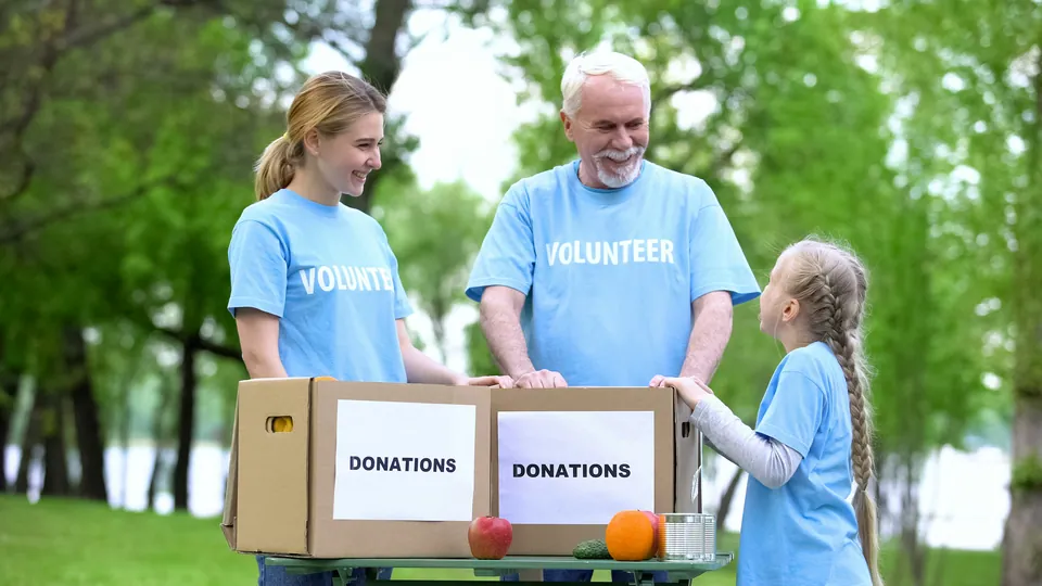 Volunteers in blue shirts packing a donations box in a park