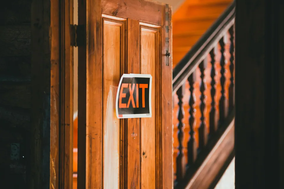 Wooden door with an EXIT sign beside a staircase