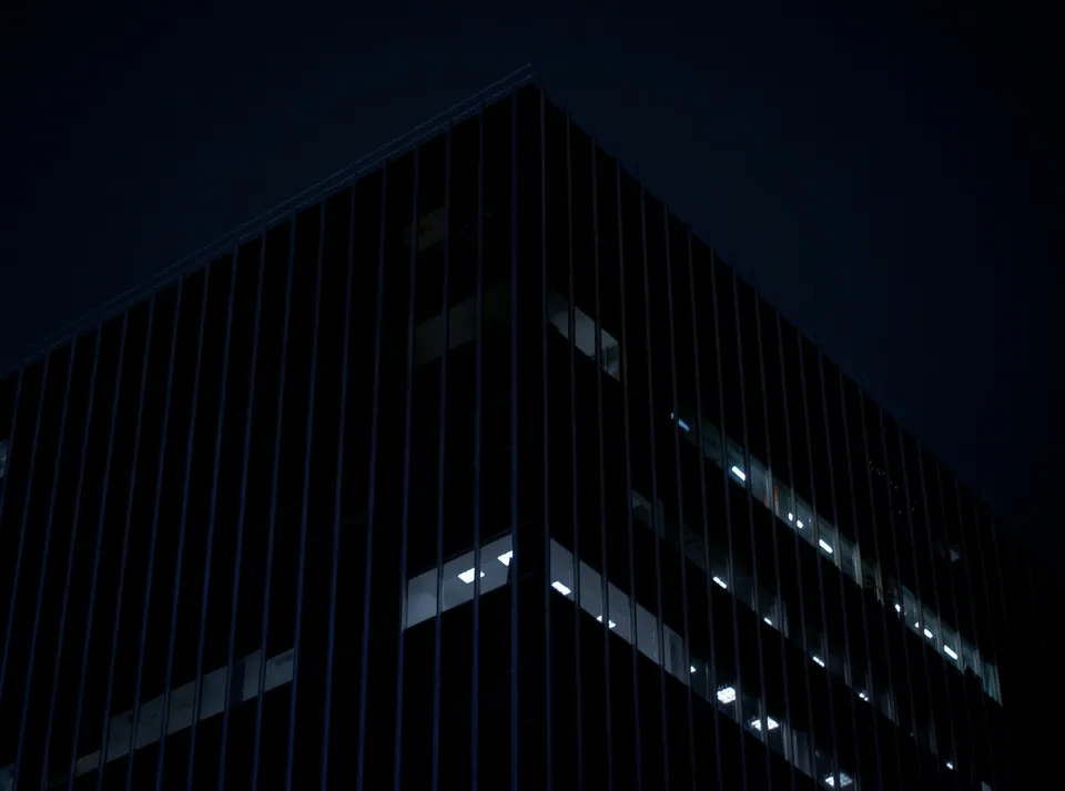 Corner of a dark glass skyscraper against the night sky