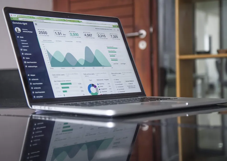 Laptop showing a portfolio analytics dashboard on a glossy table