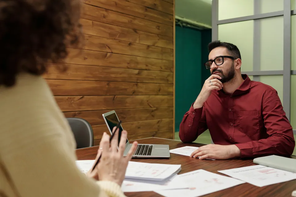 Man in glasses listening during a meeting with documents on the table