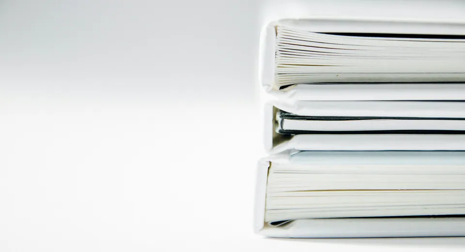 Stack of white ring binders on a white background