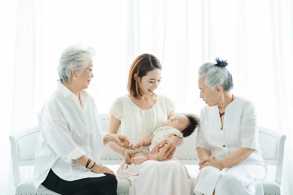 Three generations of women seated with a baby in a bright room