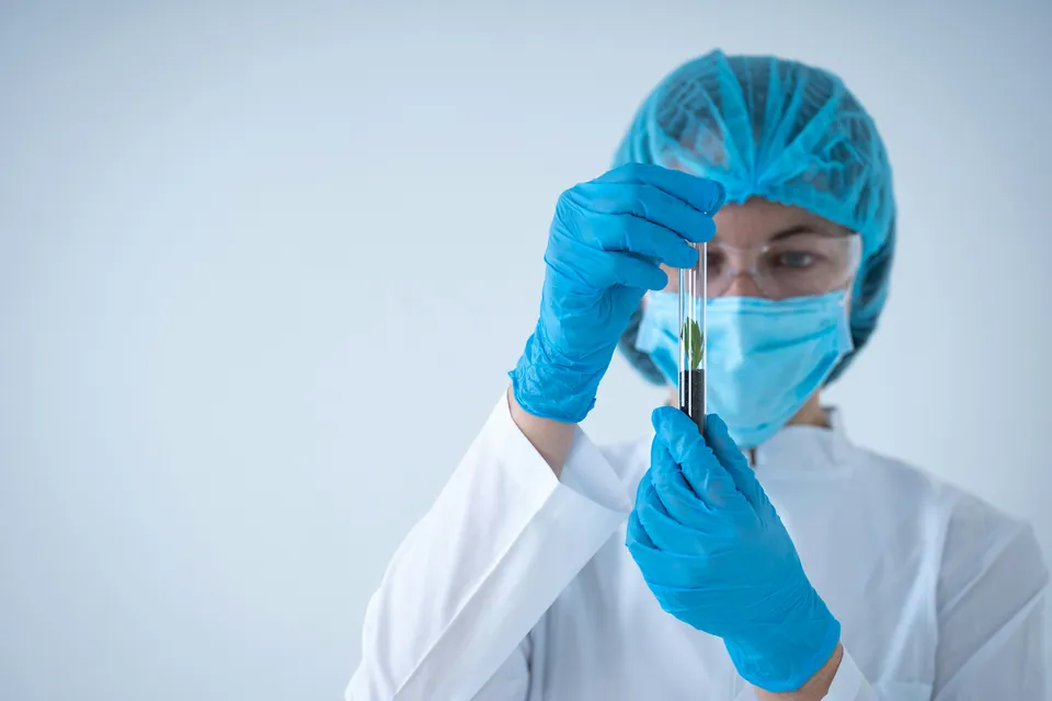 Lab researcher in protective gear examining a test tube