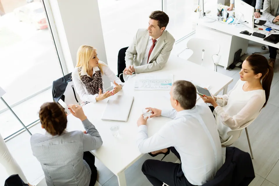Business team meeting around a white table in a bright office