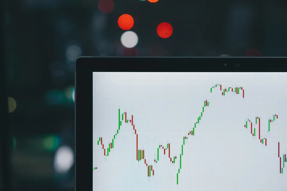 Candlestick chart on a monitor with city lights in the background