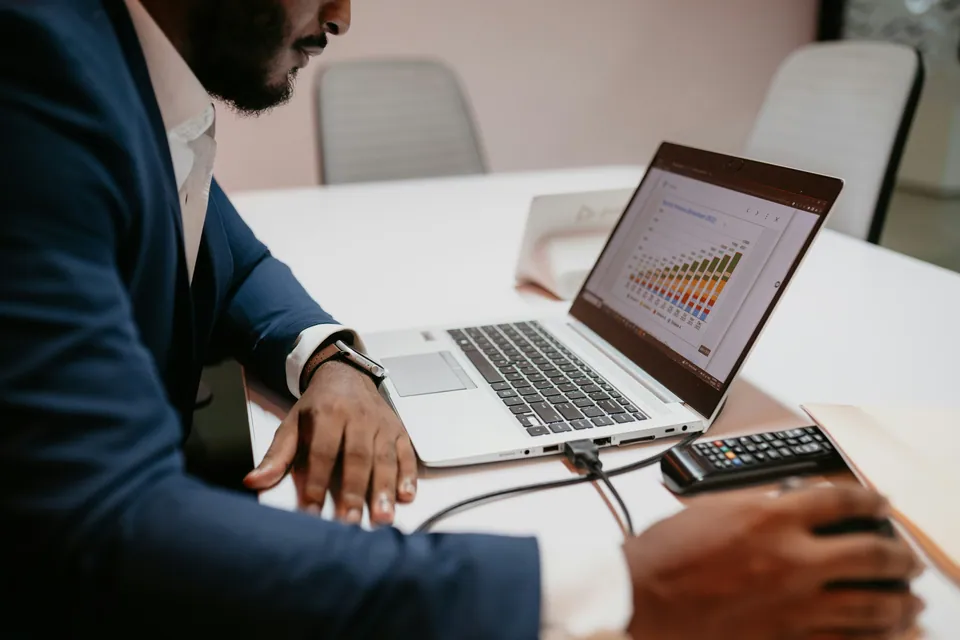 Businessman reviewing a bar chart on a laptop at a white desk