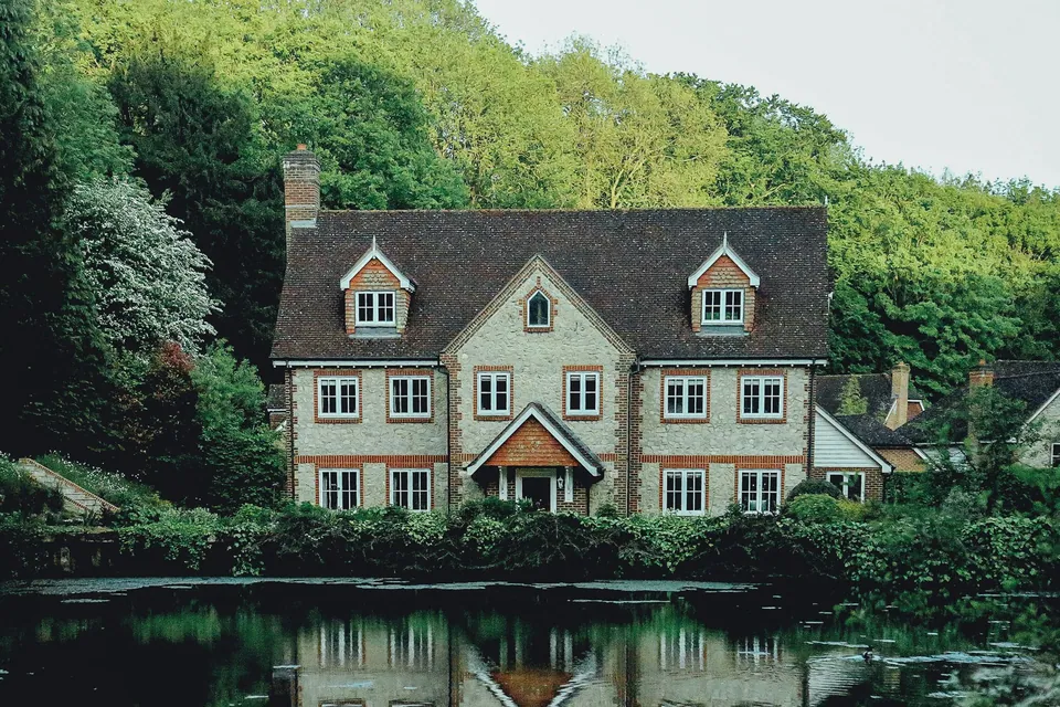 Stone country house reflected in a pond surrounded by trees