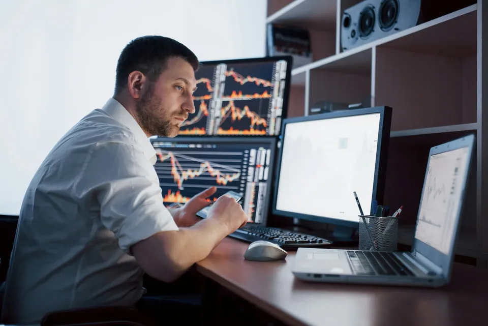 Trader at a desk with multiple chart monitors