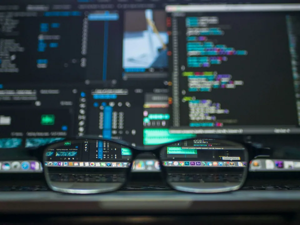 Glasses resting in front of monitors filled with code