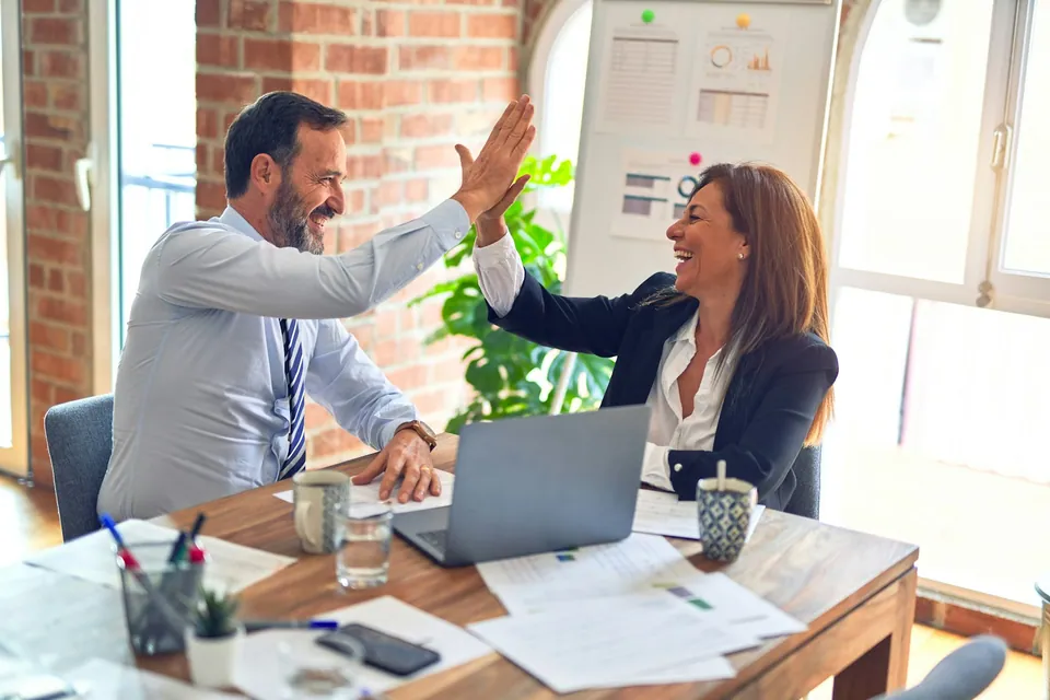 Two colleagues giving a high five at a desk