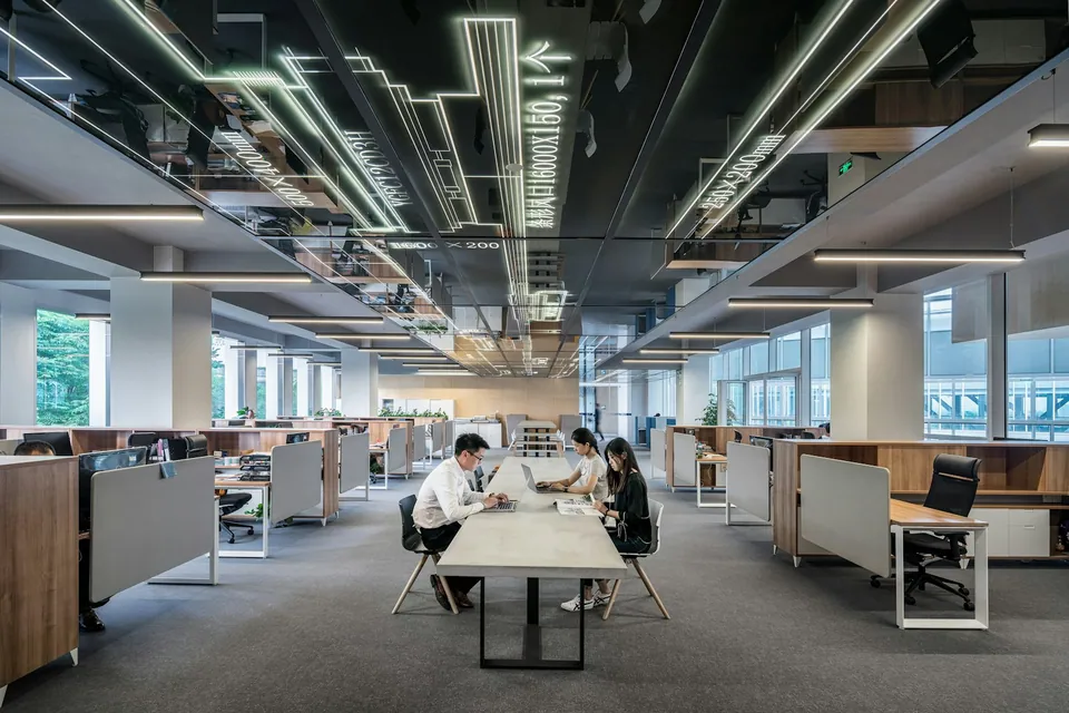 Spacious modern office with long desks and linear ceiling lights